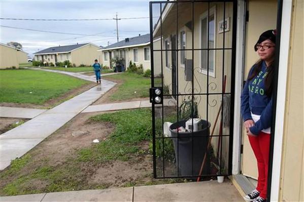 Claudia Morales, 13, at right, waits for a friend as she prepares to leave for school at a migrant laborers camp where she lives Wednesday, Nov. 19, 2014 in Watsonville, Calif. [Photo by Marcio Jose Sanchez, AP]
